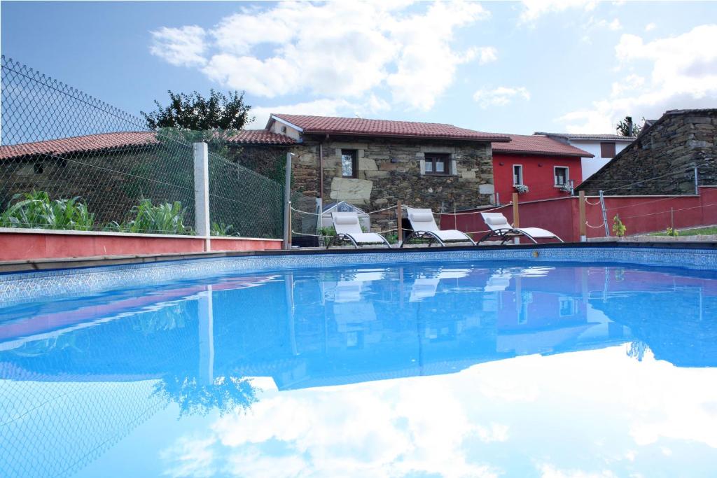 una piscina con 2 sillas y una casa en Aldea Rural A Cortiña, en Pepín
