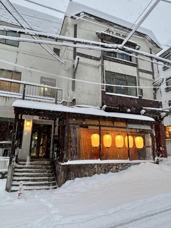 a building with snow on the front of it at Adamo Akakura in Myoko
