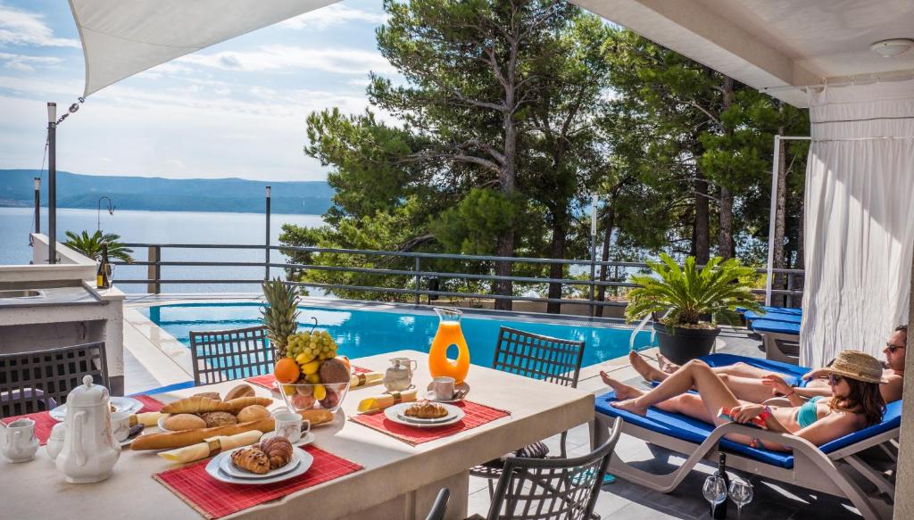 a woman laying in chairs on a patio with a table with food at Villa Marina in Omiš