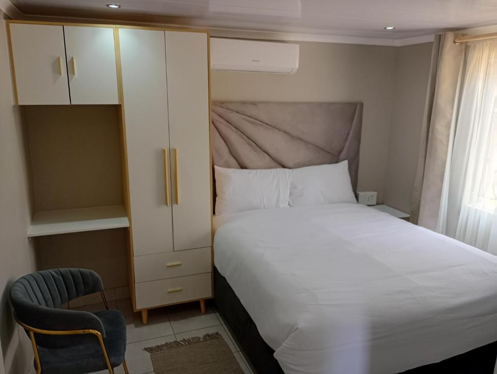 a bedroom with a bed and a cabinet and a chair at Ashdown BnB in Pietermaritzburg
