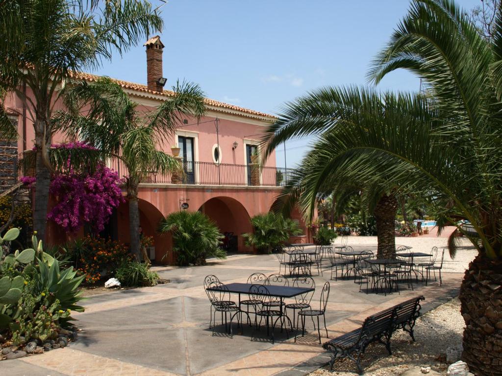 a group of tables and chairs in front of a pink building at Agriturismo Masseria Portiere Stella in Gerbini
