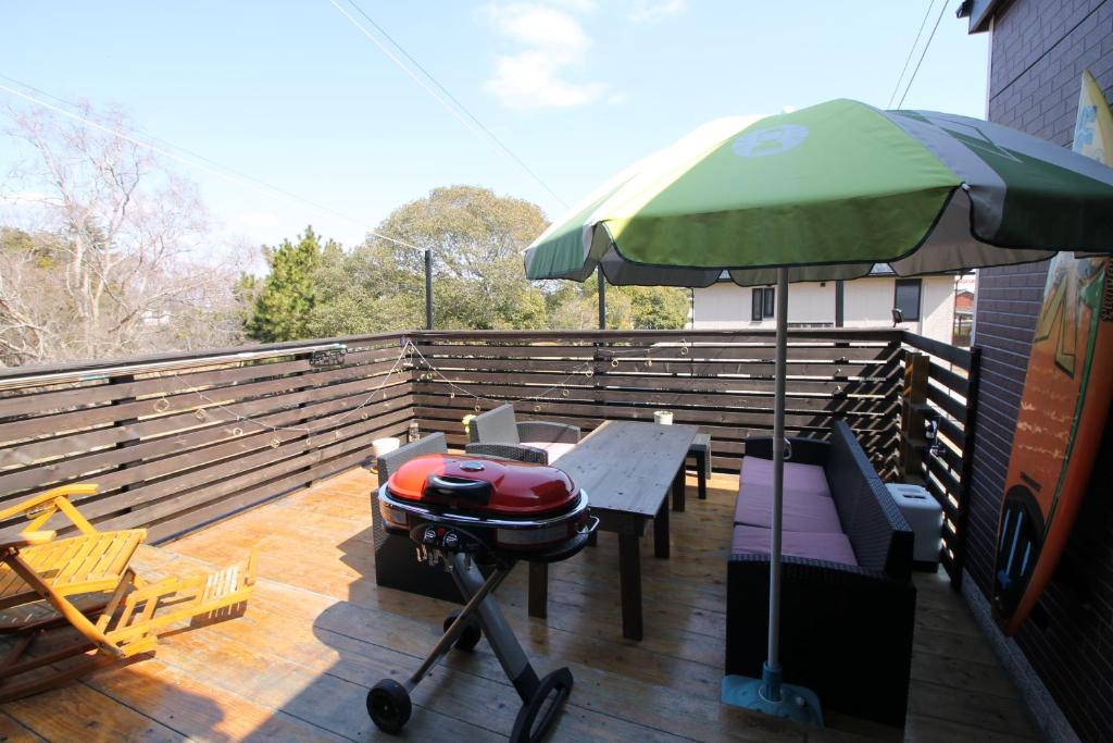 a grill on a deck with a green umbrella at Tomi house in Kariya