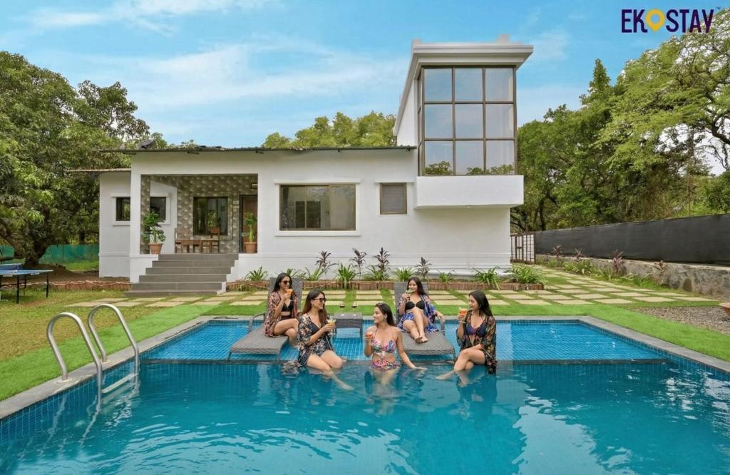a group of women sitting in the water in a swimming pool at EKOSTAY - Forestwood Villa in Alibaug
