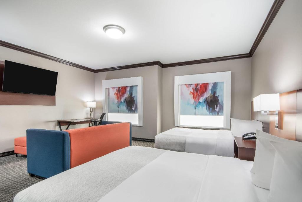 a hotel room with two beds and a flat screen tv at Hawthorn Suites by Wyndham Lubbock in Lubbock