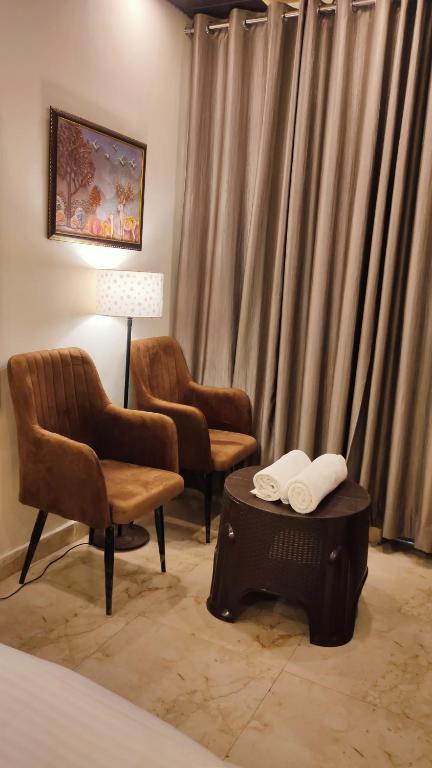 a room with two chairs and a table and curtains at Hotel SK Residency in Varanasi