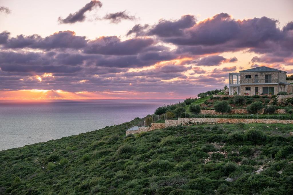 a house on top of a hill with the ocean at Villa Orizzonte - Ground Floor Apartment with shared pool & amazing view in Keri