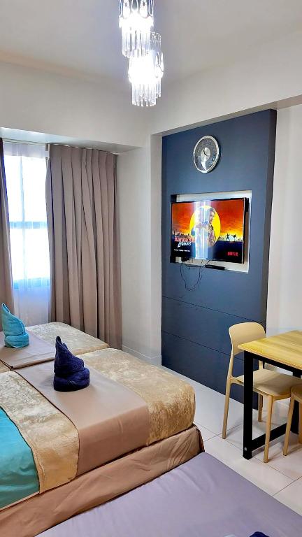a bedroom with two beds and a table and a tv at Horizons 101 Cebu- Premium Studio in Cebu City
