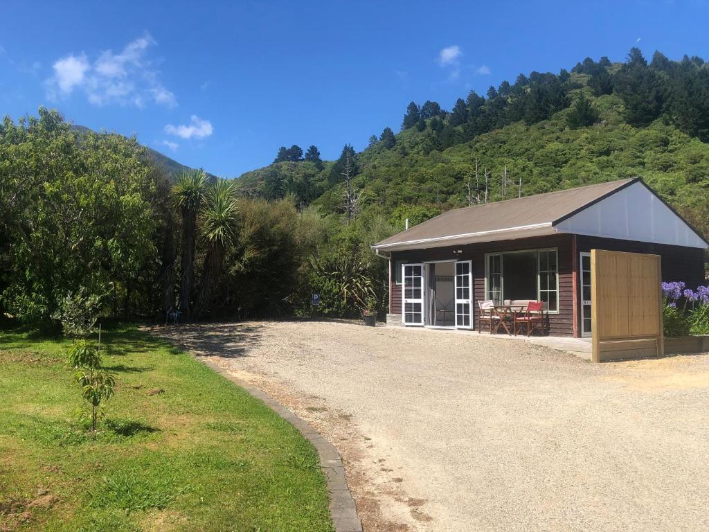 a small building on a dirt road next to a hill at The Cottage in Waikawa in Waikawa
