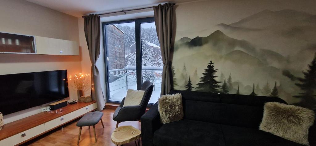 a living room with a black couch and a large window at Apartment Mumlava falls in Harrachov