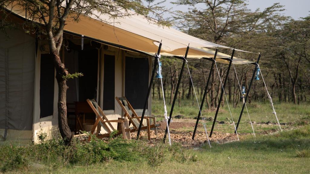 a tent with chairs in front of a house at Entepesi Tented Camp in Musiara Campsite