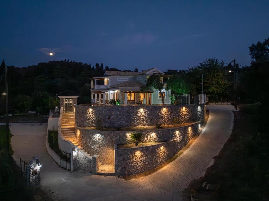 a house with a stone wall and lights at night at Villa Logas Hill in Peroulades