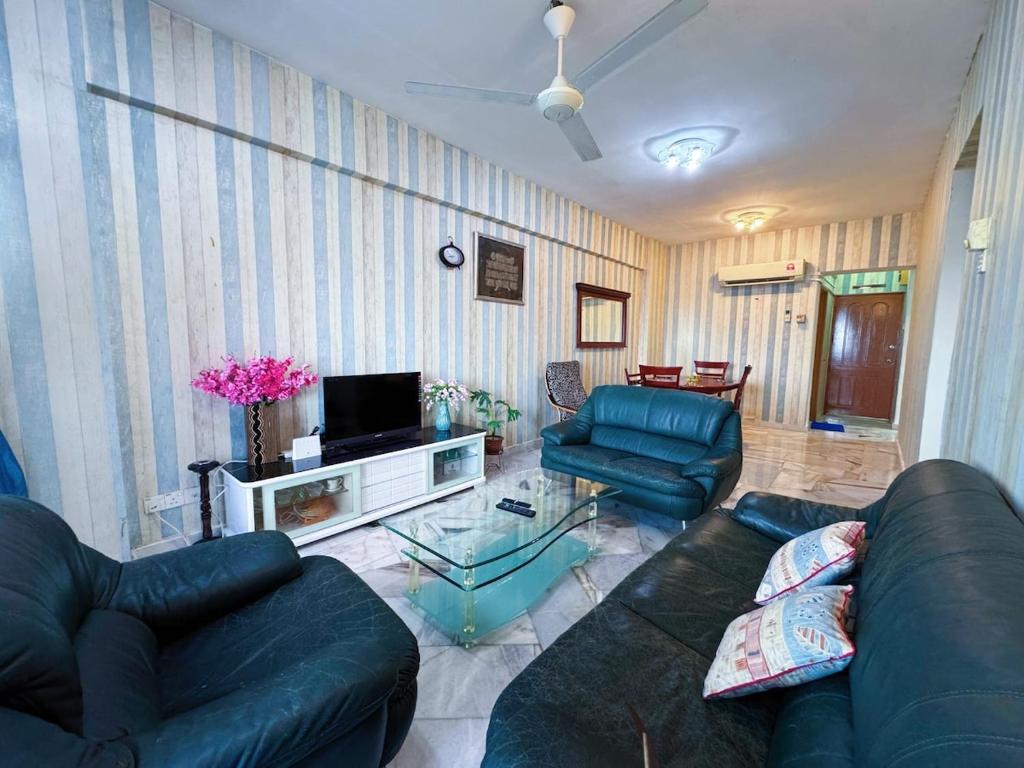 a living room with two blue couches and a tv at Beachfront Bliss Sea View Glory Beach PD Homestay in Port Dickson
