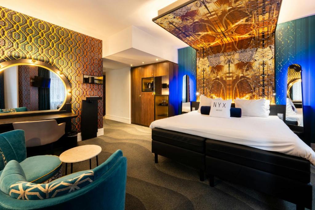 a hotel room with a bed and chairs and a mirror at NYX Hotel Amsterdam Rembrandt Square in Amsterdam