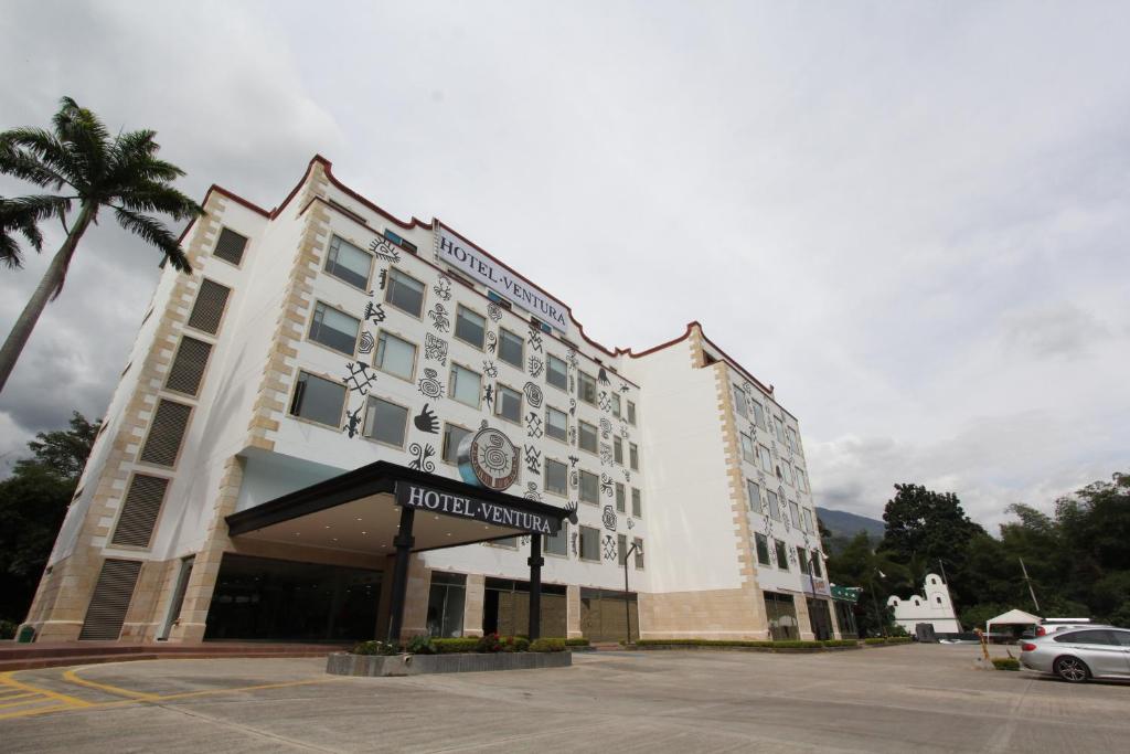 ein Hotelgebäude mit einer Palme auf einem Parkplatz in der Unterkunft Hotel Ventura in Bucaramanga