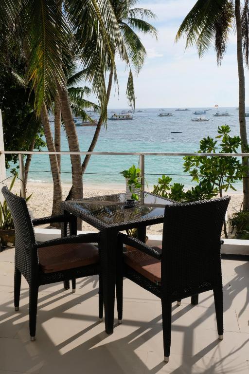 a table and chairs on a patio with the beach at Sundown Resort & Austrian Pension House in Boracay