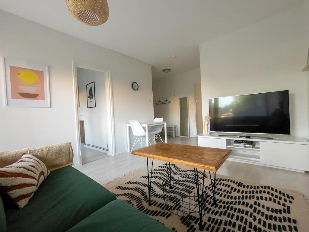 a living room with a table and a large screen tv at Bright apartment in the Center in Kajaani