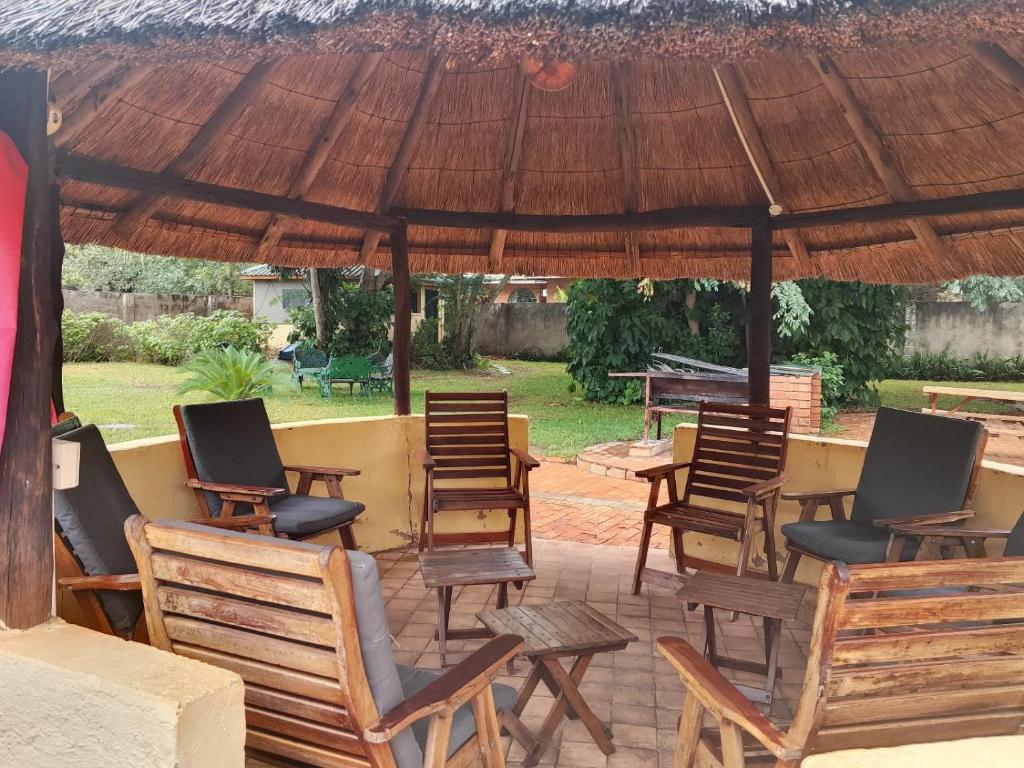 a group of chairs and tables under a large umbrella at Inkindaba Guest Lodge in Victoria Falls