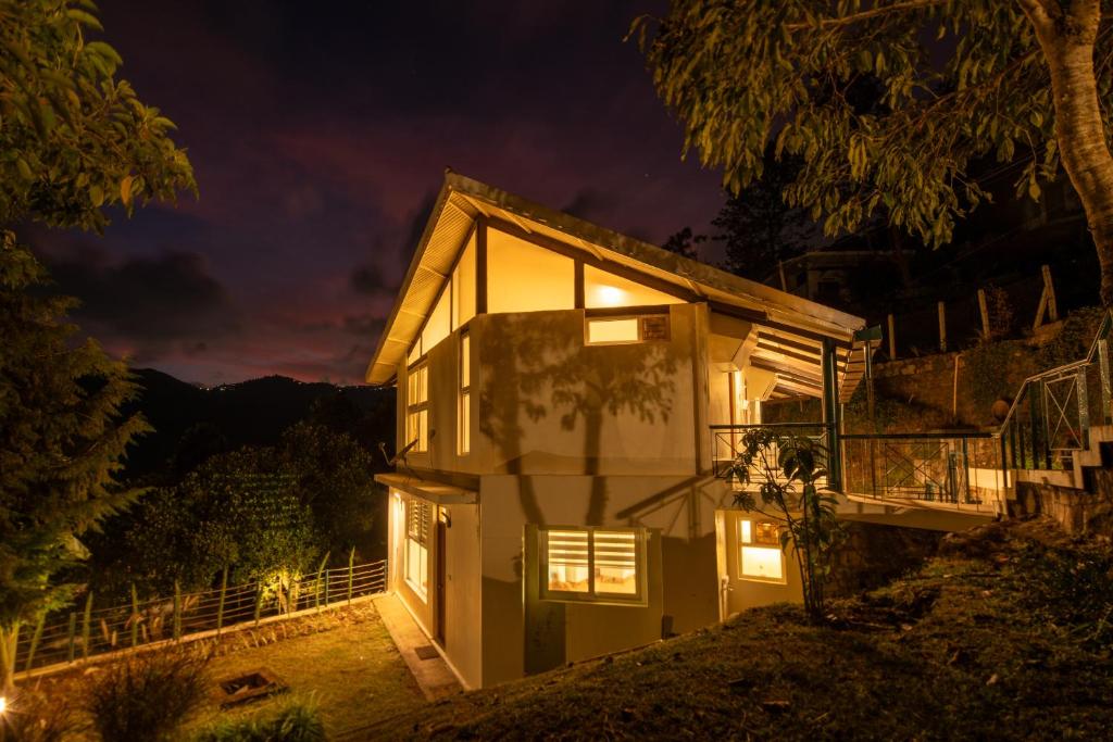 a house at night with the lights on at SaffronStays Valleyfall in Kotagiri