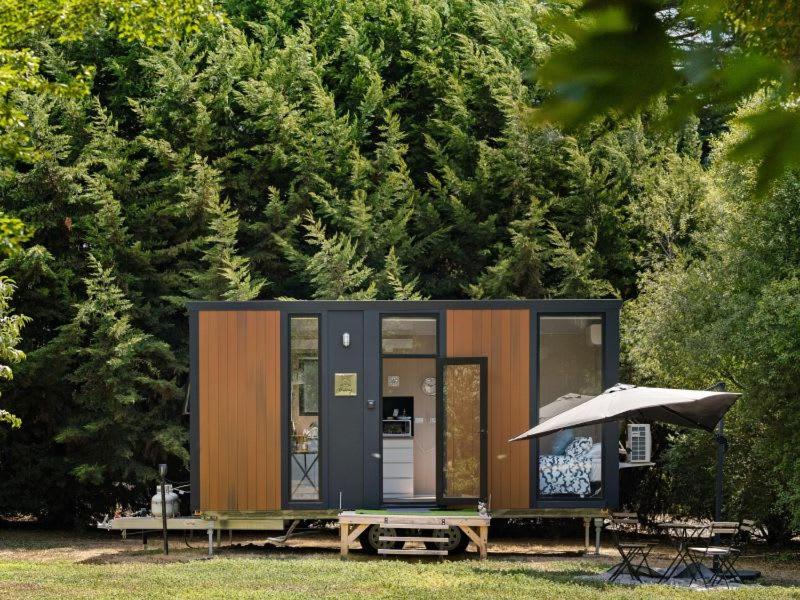 a small cabin with a table and an umbrella at Fassifern Tiny House 2 by Tiny Away in Lance Field