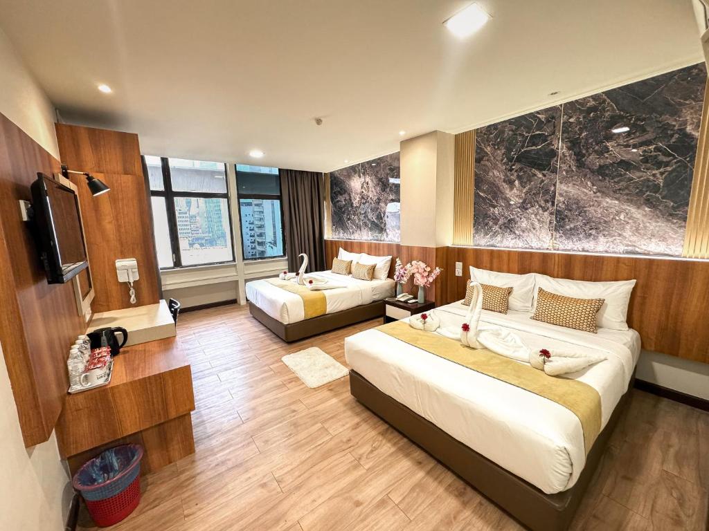 a hotel room with two beds and a television at Swiss Hotel Kuala Lumpur in Kuala Lumpur