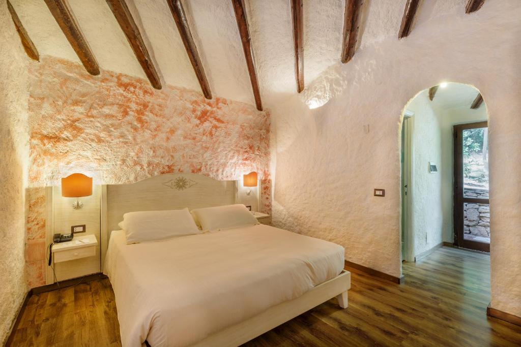 a bedroom with a white bed in a stone wall at Hotel Don Diego in Porto San Paolo