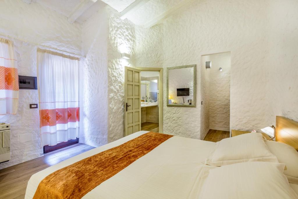 a white bedroom with a large bed and a window at Hotel Don Diego in Porto San Paolo