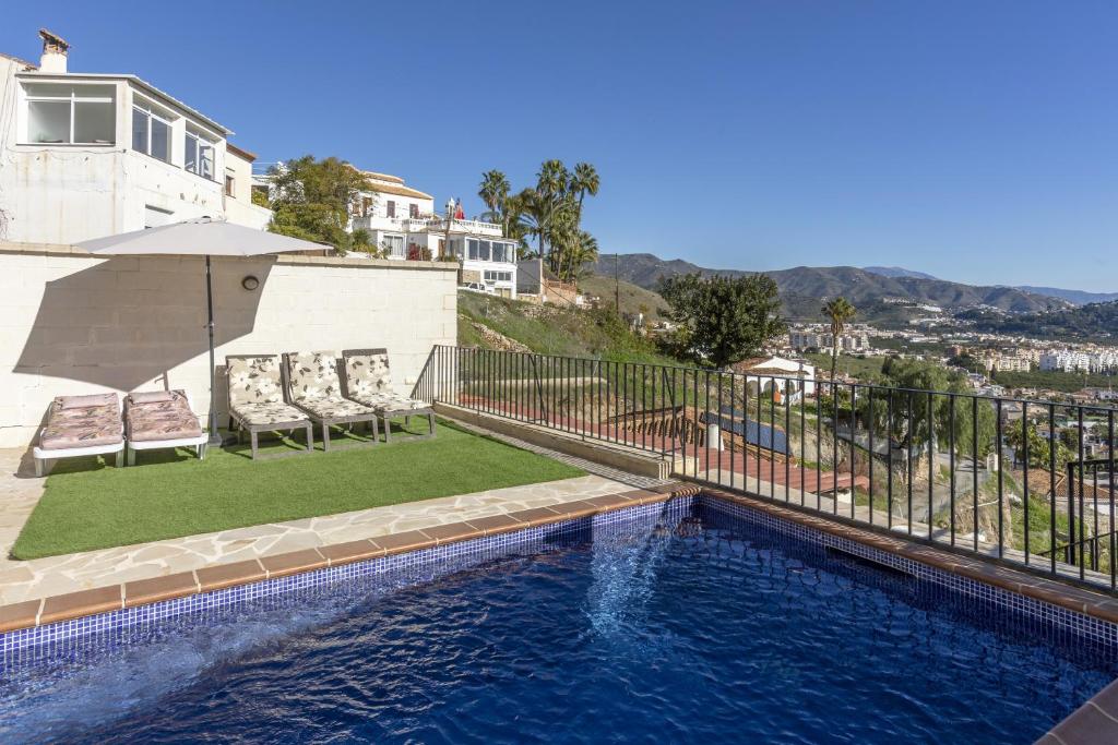 a pool with chairs and an umbrella and a house at House Miramar almuñecar in Almuñécar