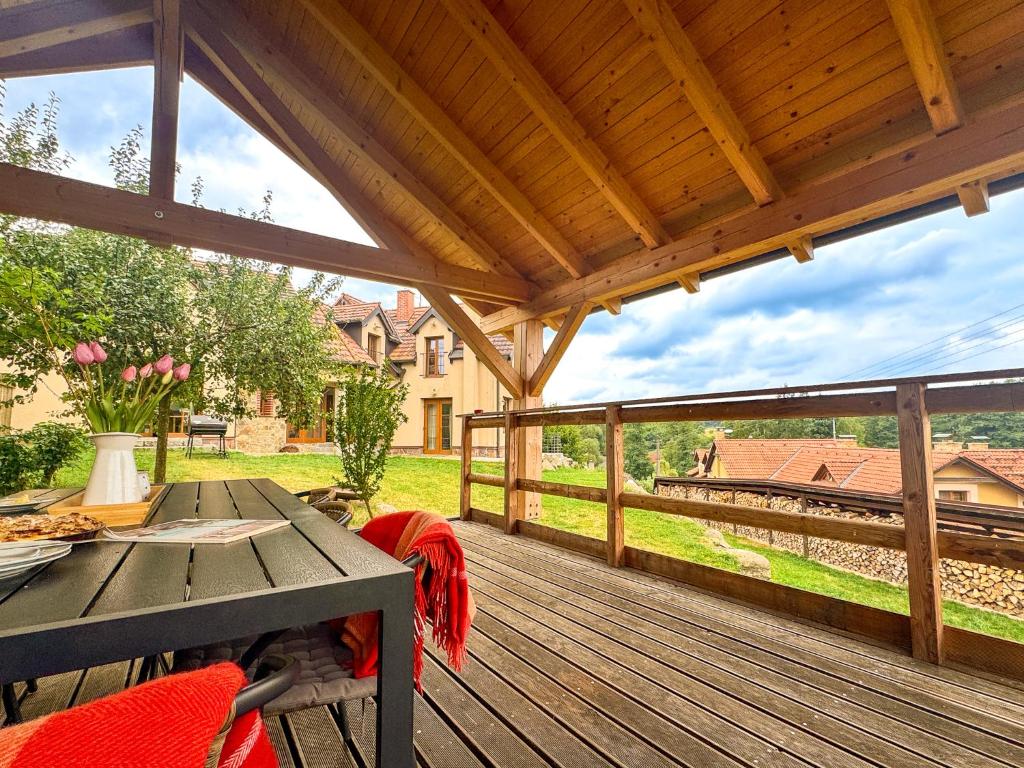 a wooden deck with a table and a view of a house at Stylová Lodge s vlastním koupáním & pergolou in Varvažov