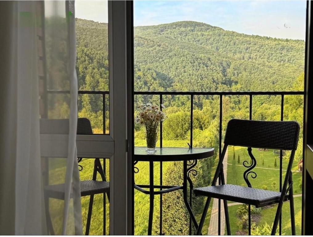 a balcony with a table and chairs and a view of a mountain at Садиба в горах in Solochyn