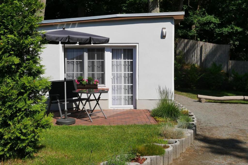 a small white shed with a table and an umbrella at Bungalow Hanseatchen in Baabe