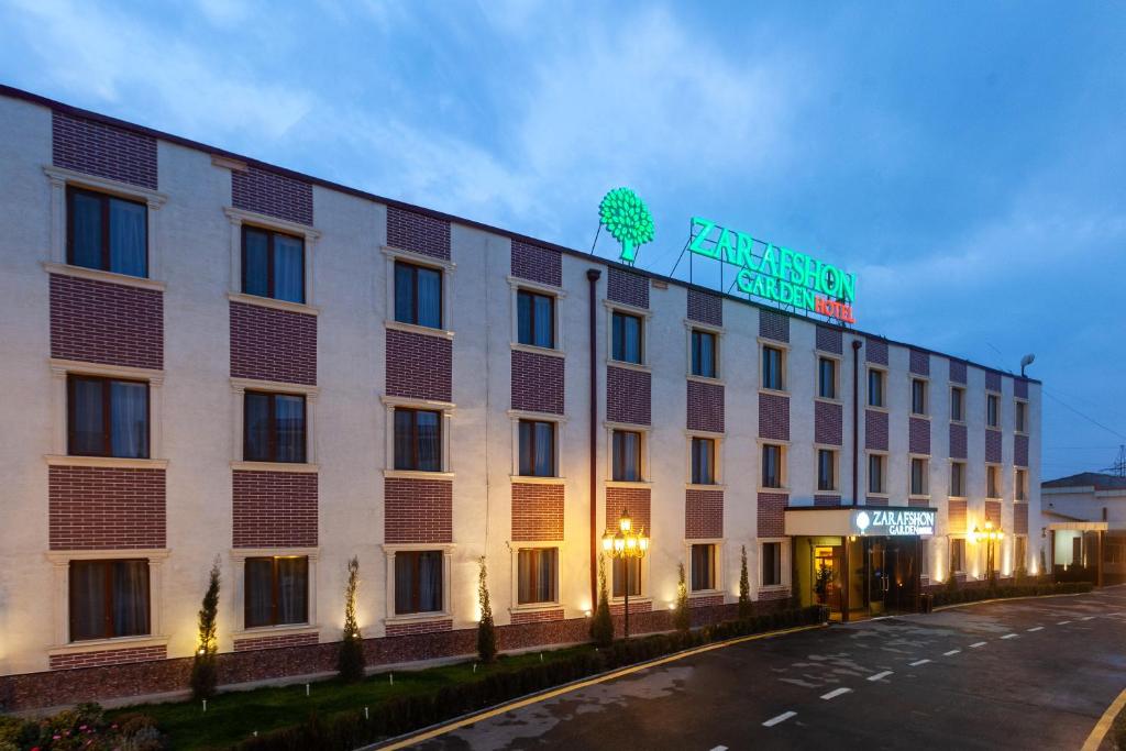 a large white building with a sign on top of it at Zarafshon Garden Hotel in Bukhara