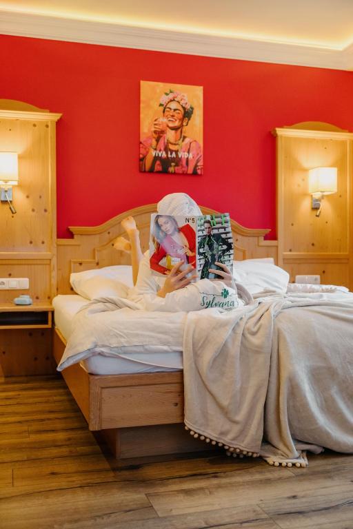 a woman laying on a bed in a red room at Sylvana's Wohlfühl Hotel in Mayrhofen