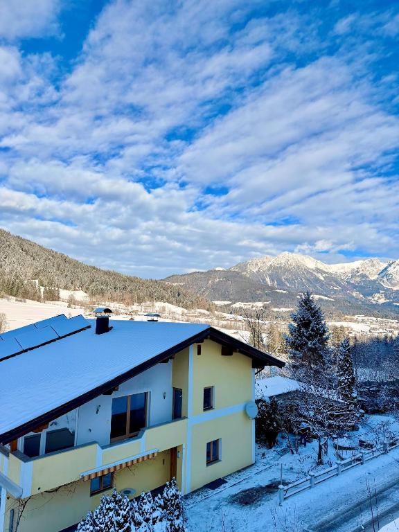 a house covered in snow with mountains in the background at Alps Living Söll in Söll