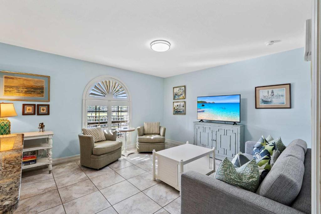 a living room with a couch and chairs and a tv at Le Monaco - 1 BR Romantic Condo! Getaway Steps from 5th Ave S Stylish Coastal Retreat with King Bed Beach Access and Prime Location, Near Dining Shopping and Sunset Views! in Naples
