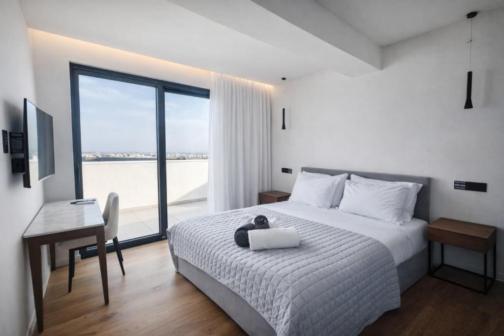 a bedroom with a bed with a desk and a window at Sky Suites Nicosia in Strovolos
