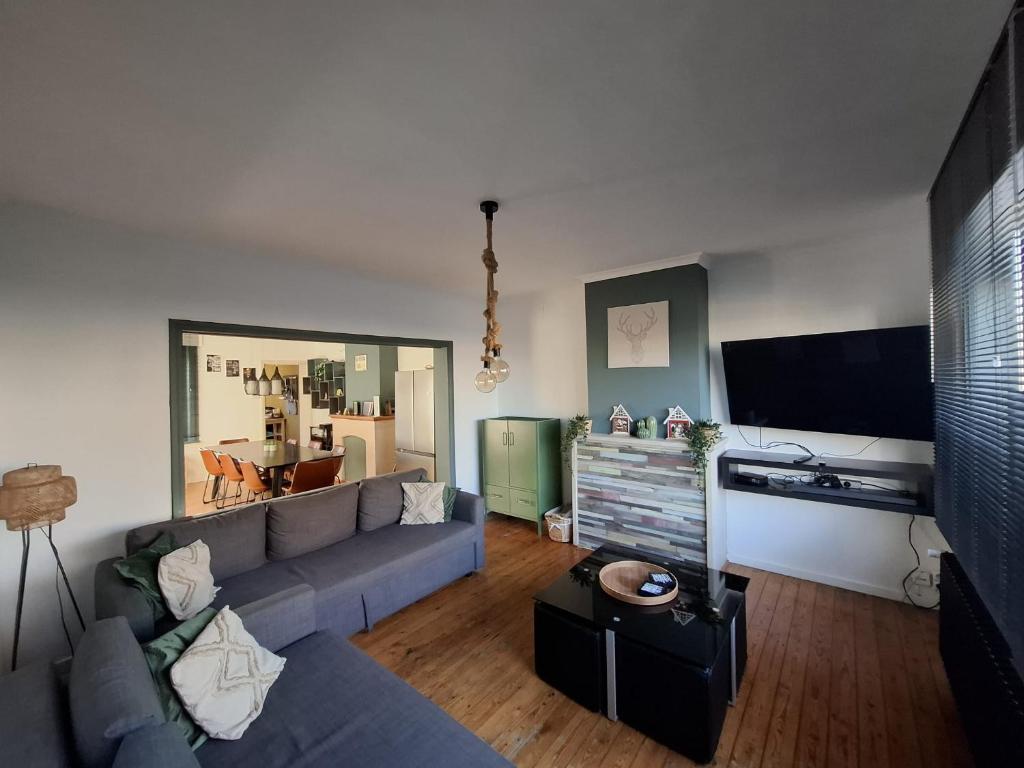 a living room with a blue couch and a flat screen tv at Vakantiewoning dEreplatse in Zuienkerke