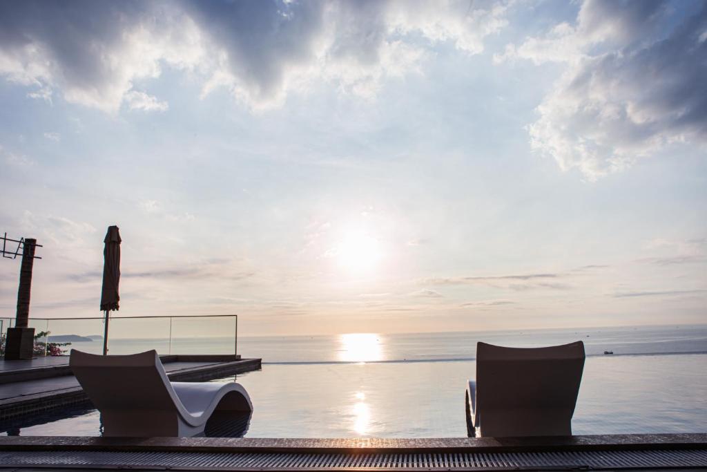 two chairs sitting on a dock near the water at Apec Mandala Chambay Mui Ne - Oceanic Studio in Mui Ne