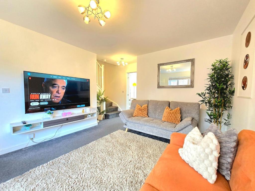 a living room with a couch and a flat screen tv at The Charm Luxury House - 8mins to NEC, Birmingham Airport in Marston Green