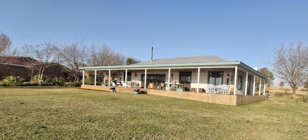 a house with a porch with chairs on a lawn at Riverside Farm in eMalahleni