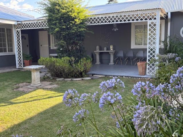 a house with a garden with purple flowers and a table at Silver Linings Cottage in Parys