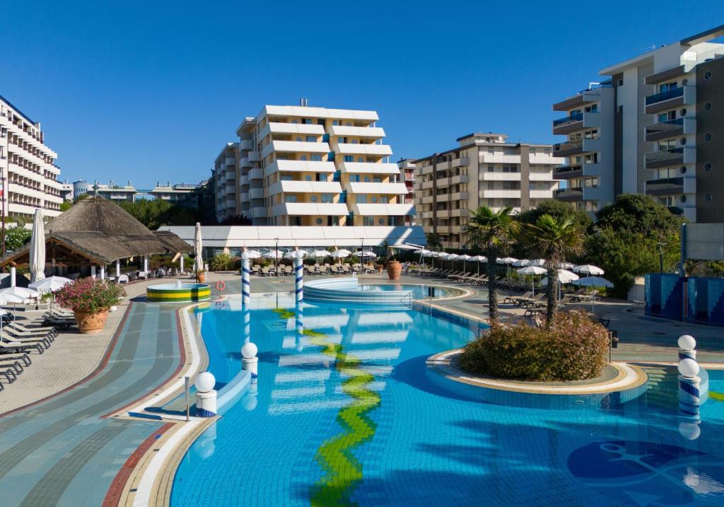 a pool at a resort with buildings in the background at Aparthotel Holiday in Bibione