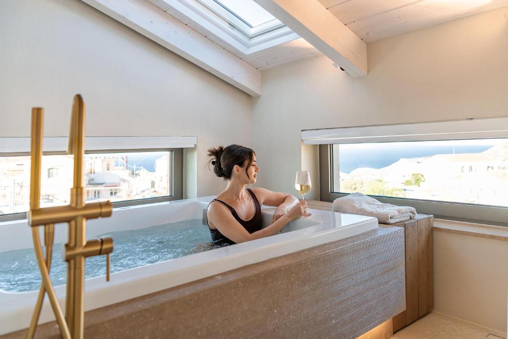 a woman sitting in a bath tub with a window at Villa Villagio Rosso in Kókkinon Khoríon