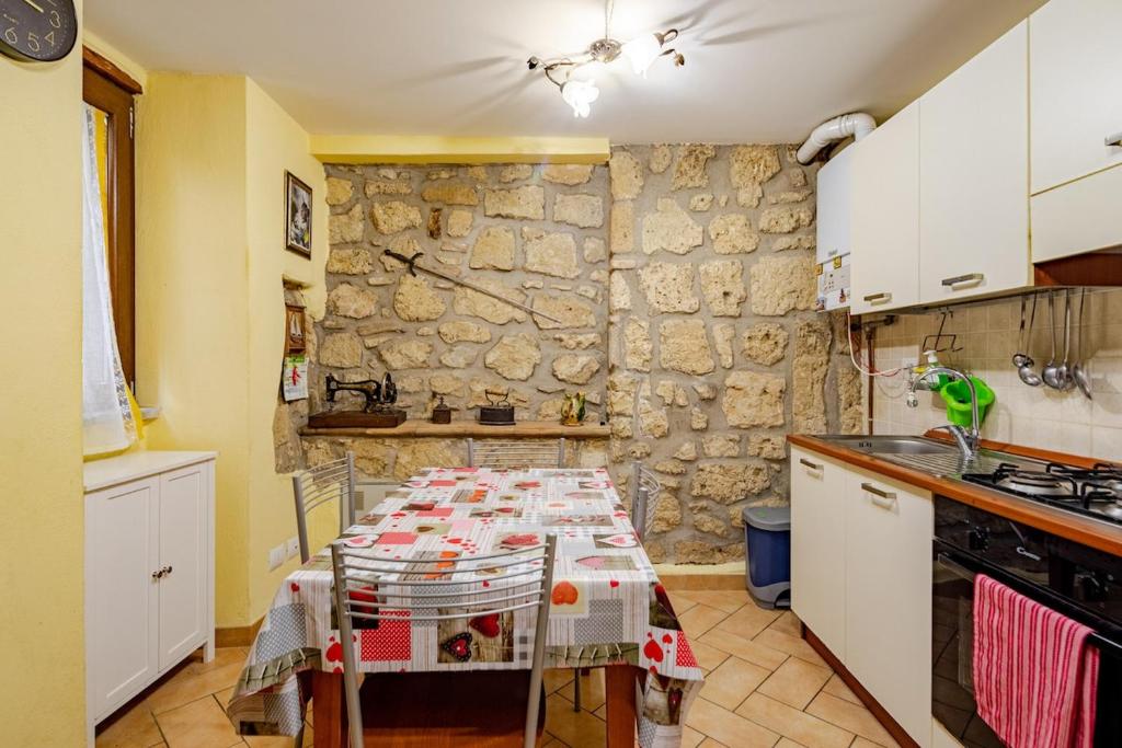 a kitchen with a table and a stone wall at The Stone House Historic Center in Grotte di Castro