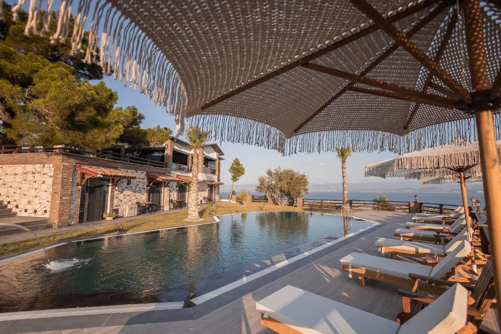 a pool at a resort with chairs and umbrellas at Kaira Kazdaglari in Edremit