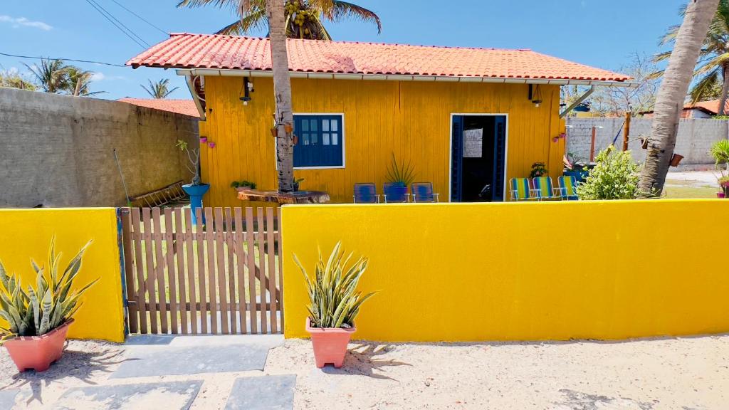 a yellow house with a fence in front of it at Casa da Barra Tutóia in Tutóia