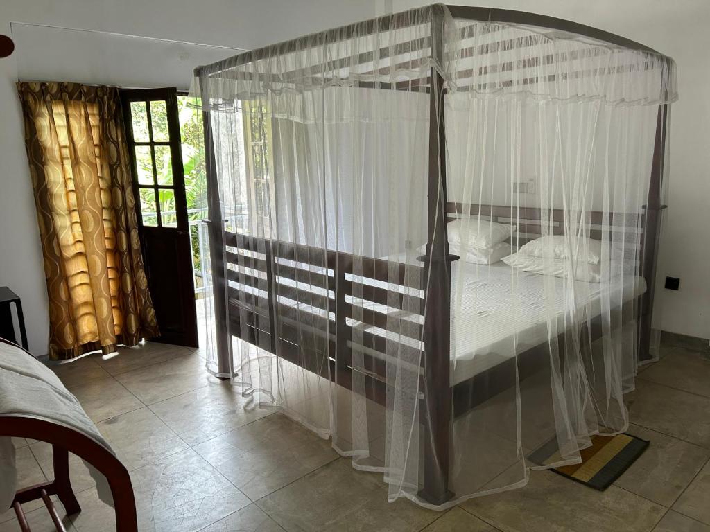 a canopy bed with white curtains in a bedroom at Hikka Residence 98 in Hikkaduwa