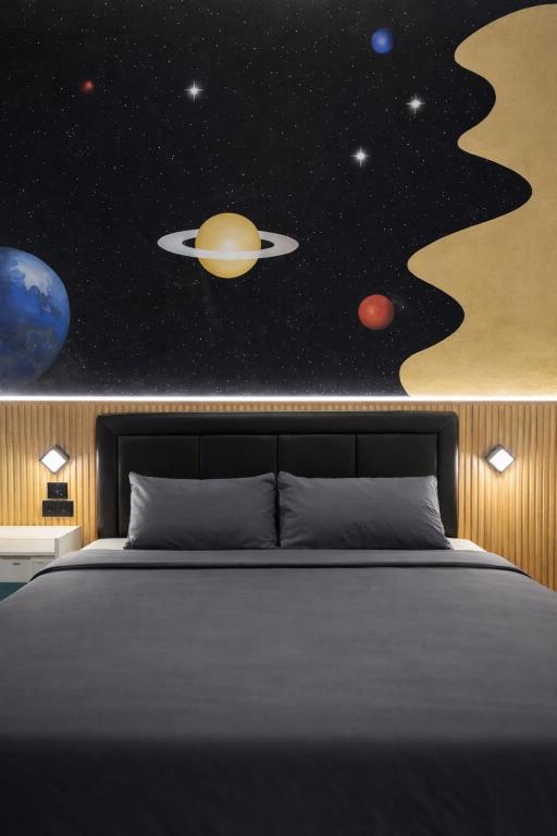 a bedroom with a bed with a planet and stars at De Azka Style Syariah in Malang