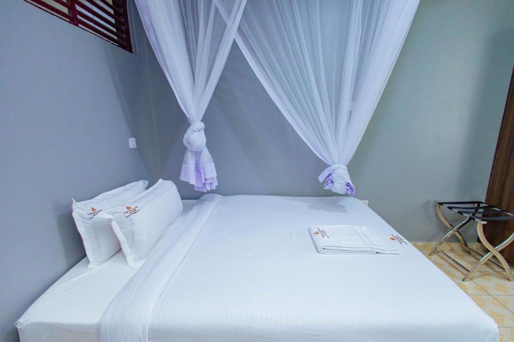 a bedroom with a white bed with curtains at The VIP Luxury CBD in Kisumu