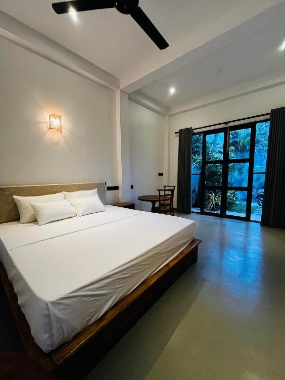 a bedroom with a large bed and a large window at Ancy Villa in Dickwella