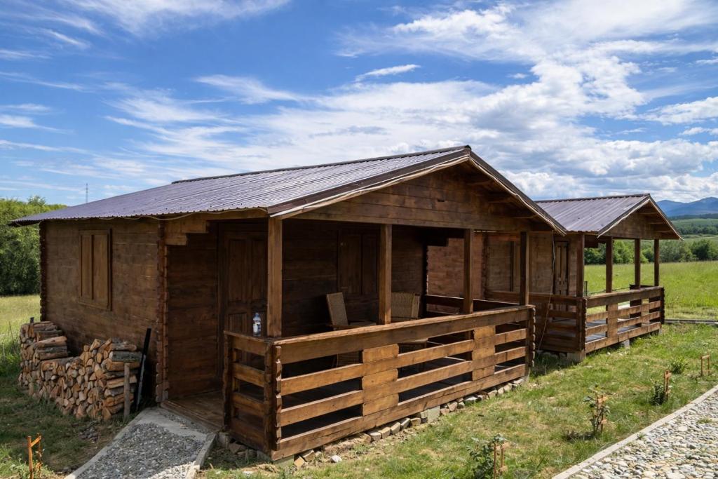 a wooden building with a metal roof on a field at Cabanuta Din Deal in Racoviţa